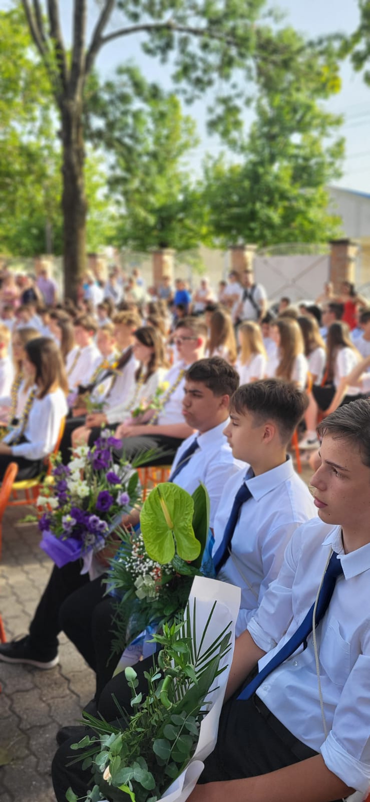 Graduating students seated with bouquets